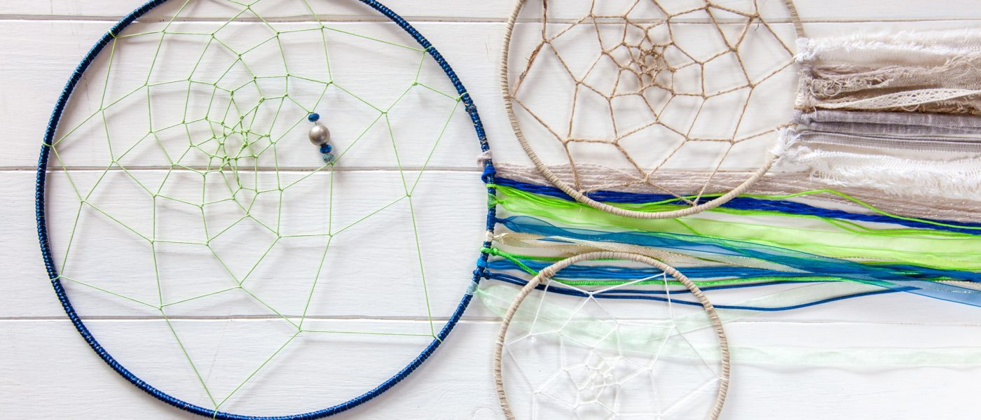 Trois dreamcatchers ou attrape-rêves posées sur une planche en bois blanc.