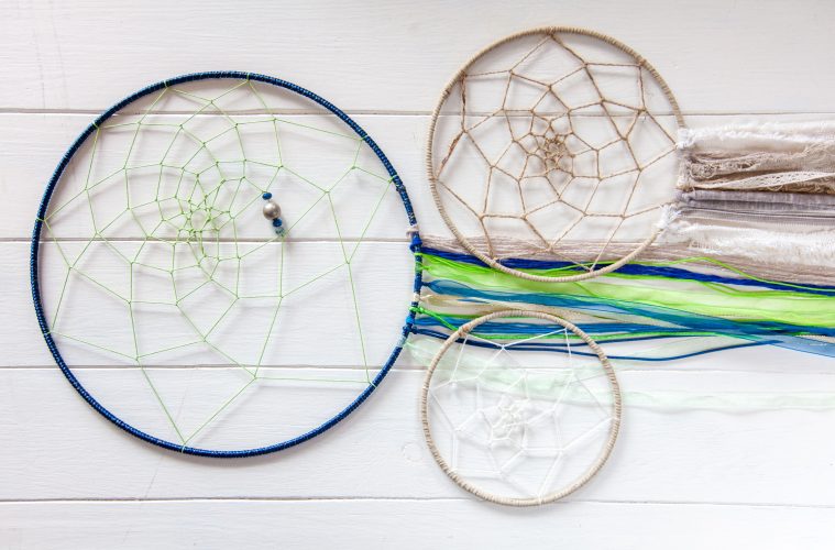 Trois dreamcatchers ou attrape-rêves posées sur une planche en bois blanc.