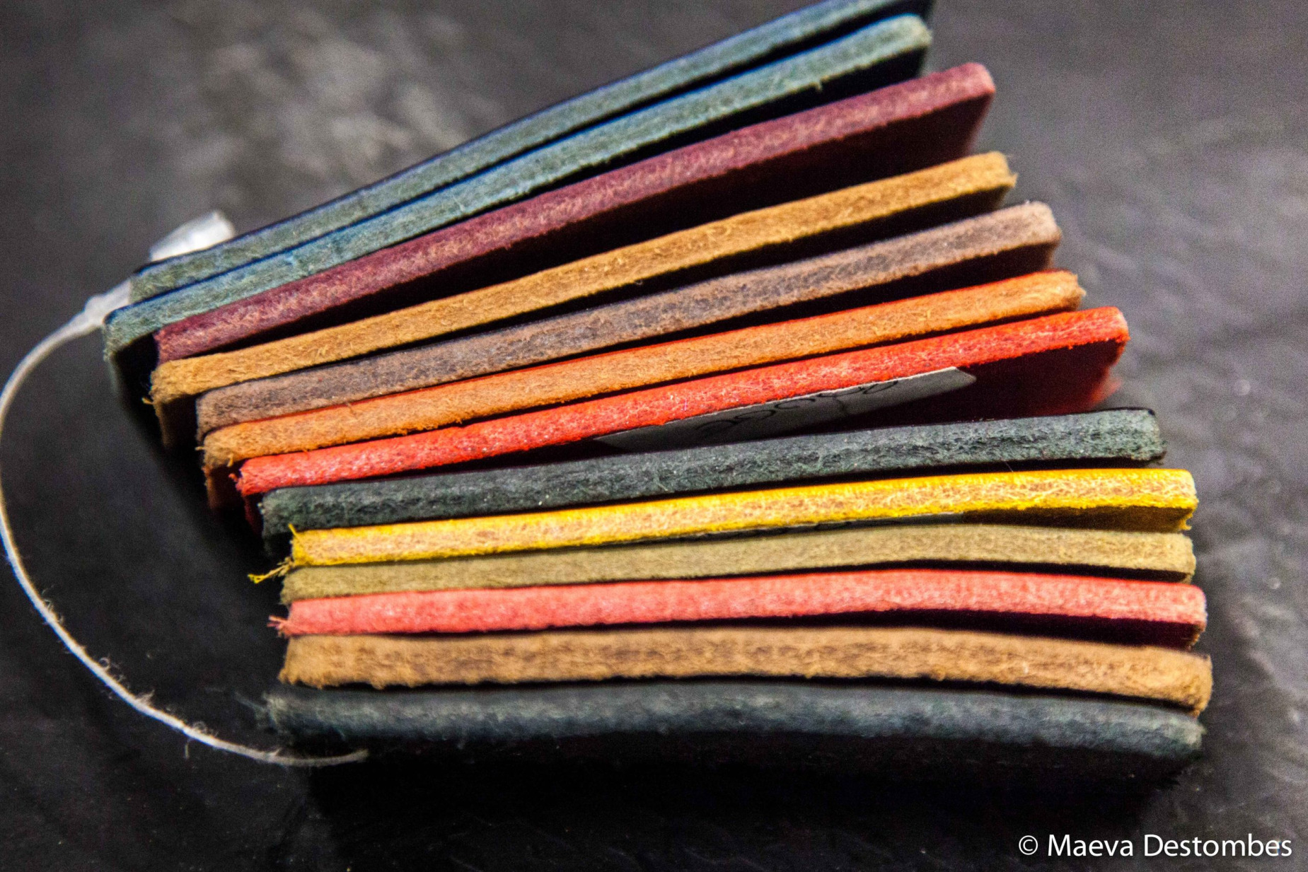 Des échantillons en cuir de différentes couleurs empilés sur une surface noire.