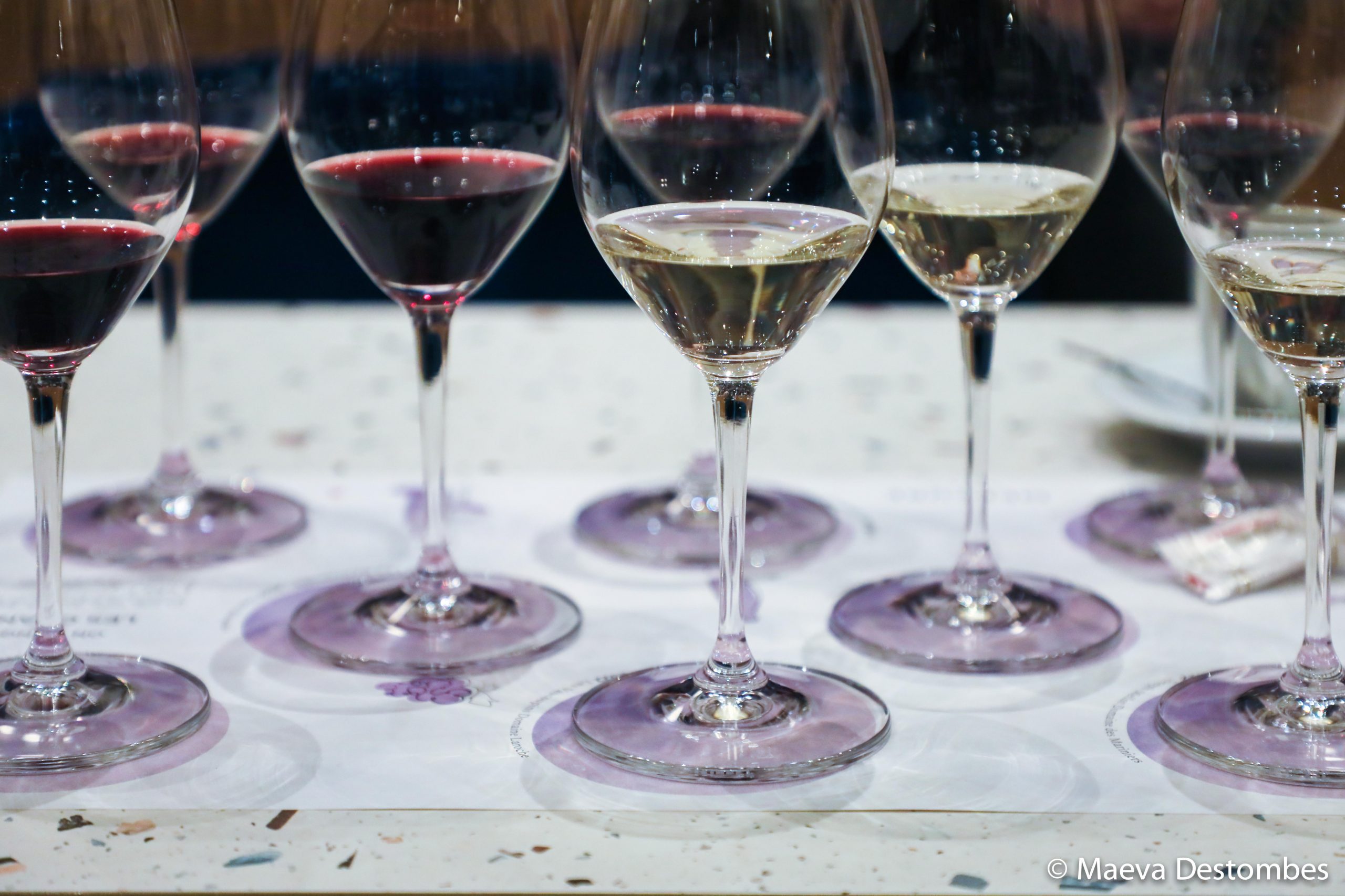 Une table avec de nombreux verres à vin et une nappe blanche.