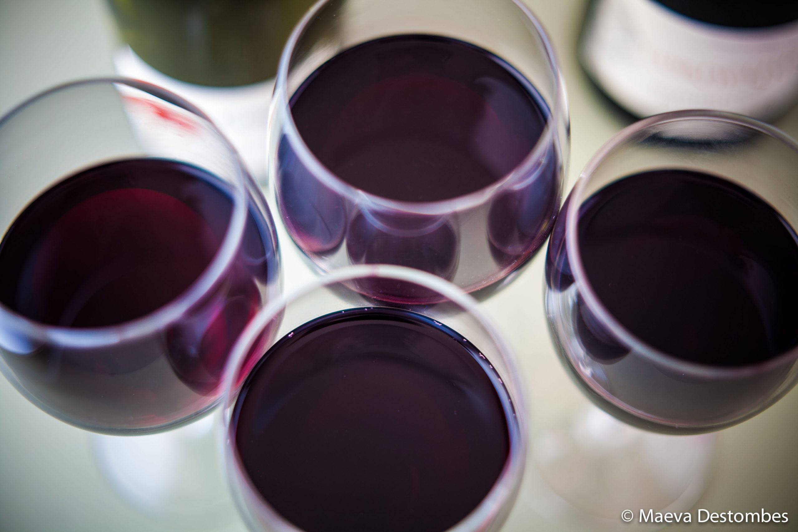 Vue plongeante sur quatre verres de vin rouge.