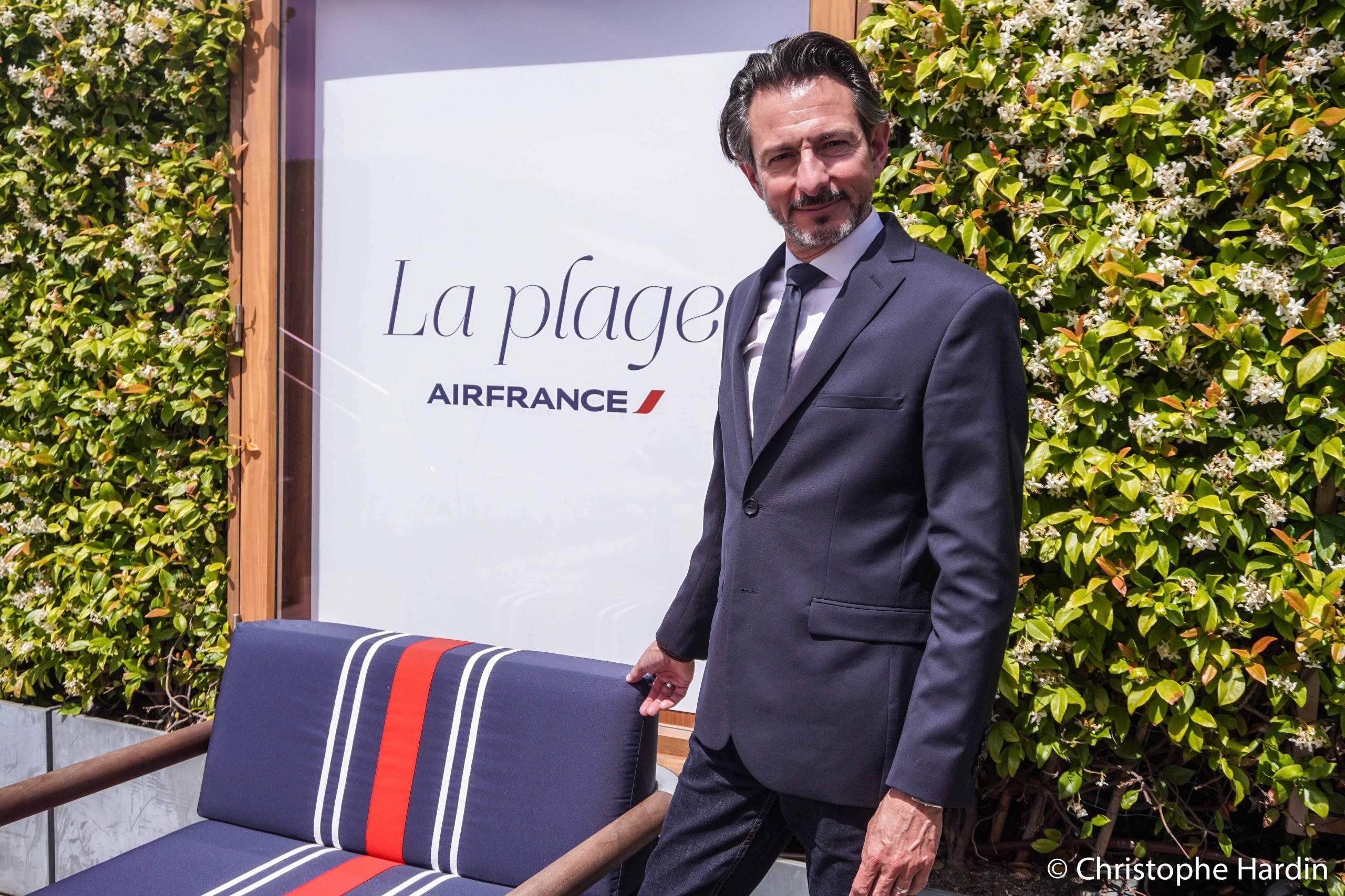 Fabien Pelous, Directeur Expérience Client Air France, posant à côté d'une chaise avec un tissu bleu blanc rouge et l'enseigne La Plage Air France.