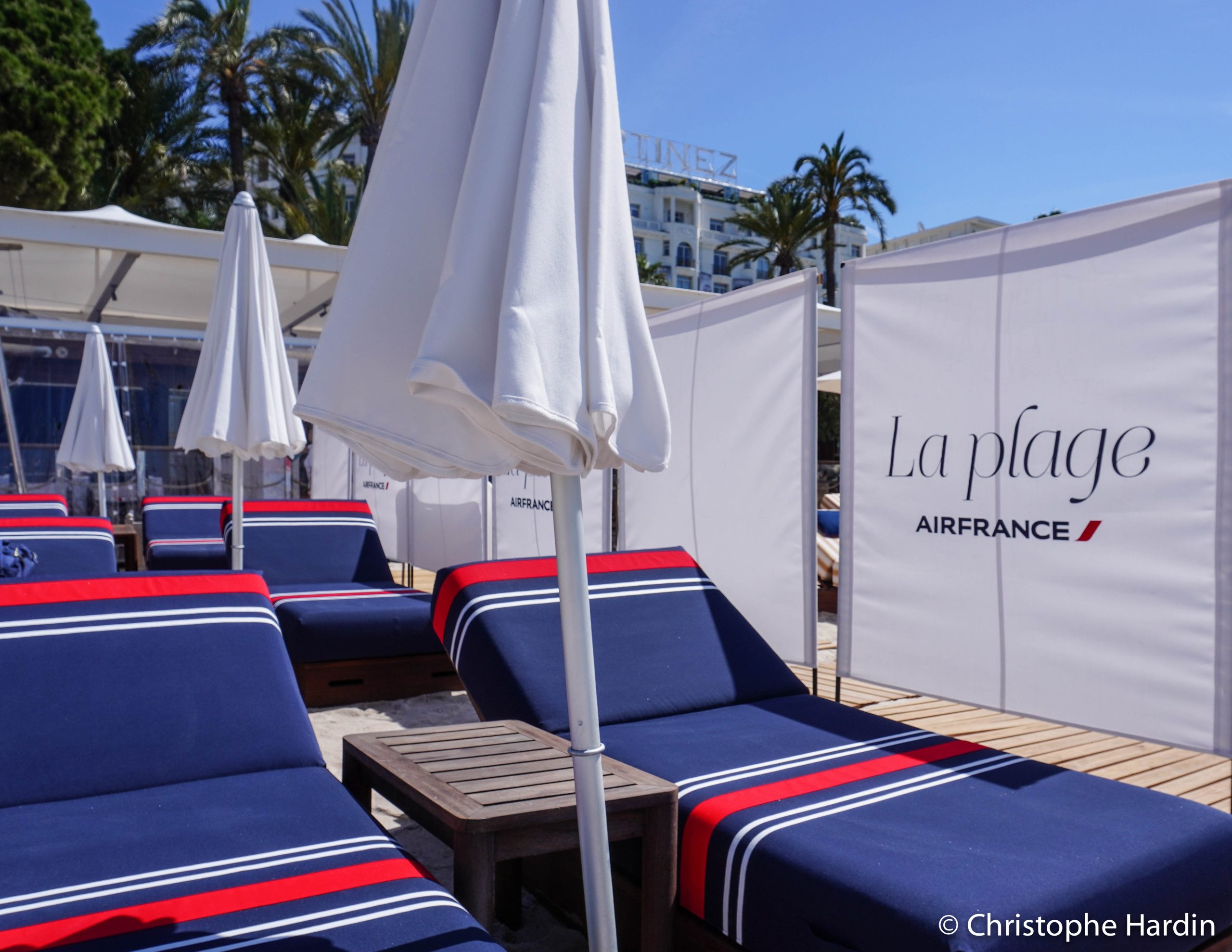 Des transats aux couleurs de la compagnie aérienne Air France bleu blanc rouge sur la plage de Cannes avec l'hôtel Martinez en arrière plan.