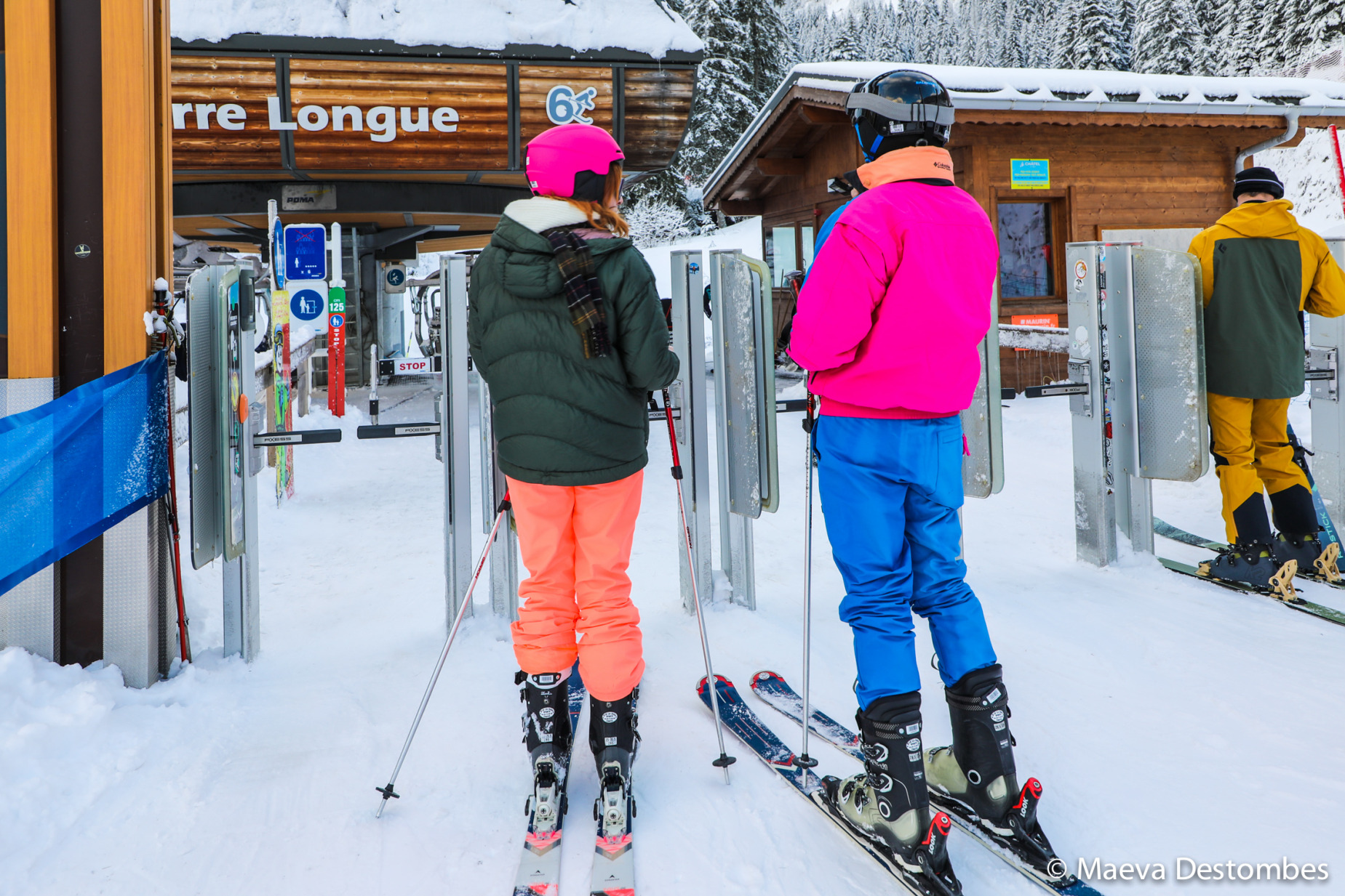 Three skiers dressed in colorful ski clothes and with skis on their feet prepare to take the telesiege in the Portes du Soleil resort-village of Chatel in Haute-Savoie in France on December 20 of 2024. Trois skieurs vetus de vetements de ski tres colores dote de skis aux pieds s appretent a prendre le telesiege dans la station de Chatel station-village des portes du soleil dans la Haute-Savoie en France le 20 decembre 2024.