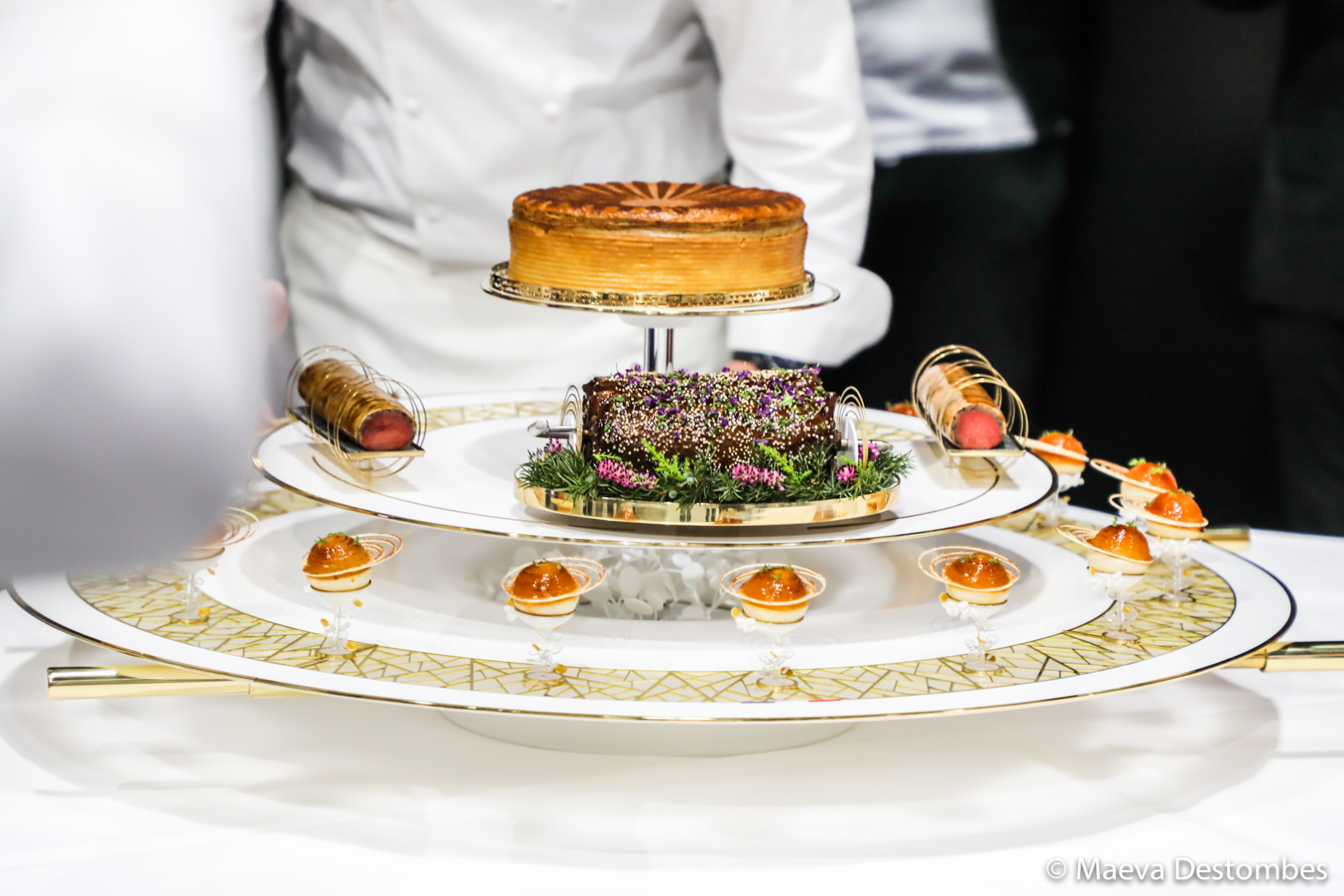 Le thème plateau de la France au Bocuse d'Or 2025 avec au centre une selle de chevreuil rôtie à la broche farcie au foie gras et filets mignons, écailles de champignons, sauce gibier infusée aux poivres et mélilot.